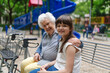 © Halfpoint - Grandma with walker picking up young girl from school at afternoon, spending time with senior grandmother in city park, sitting on bench in children playground.