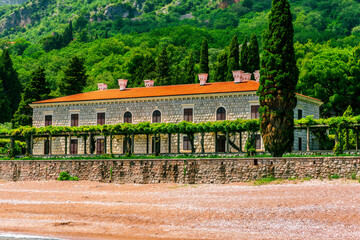 beautiful summer season landscape of scenic coast with beach and nice architecture building of hotel or palace with awesome green garden and great mountains on background