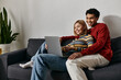© LIGHTFIELD STUDIOS - A happy multicultural couple smiles while relaxing together on a couch and browsing the internet on a laptop.