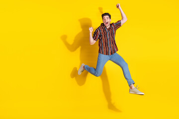 Poster - Full length portrait of nice young man jump raise fists empty space wear shirt isolated on yellow color background