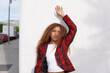 © VISTA by Westend61 - Young curly haired woman wearing red checked blazer and leaning on white wall