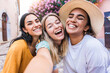 © Davide Angelini - Three beautiful young women smiling at camera outside - Happy girls friends taking selfie pic with smart mobile phone - Female tourists enjoying summertime vacation together - Technology concept