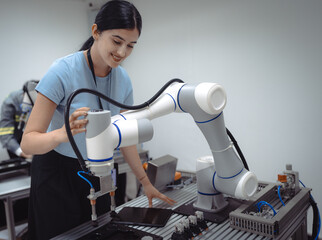 Wall Mural - Computer science development engineer working on robotic arm connection control at electronic futuristic technology academy. Modern hispanic woman training smart industry 4.0 automatic engineering.