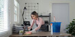 © Natee Meepian - Young Maid Cleaning Modern Office Desk with Cleaning Supplies in Bright Room