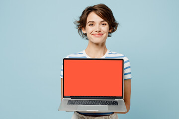 Young IT woman wears striped t-shirt casual clothes hold use work on laptop pc computer with blank screen workspace area isolated on plain pastel light blue cyan background studio. Lifestyle concept.