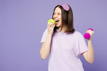 Poster - Young strong calm woman wear pyjamas jam sleep eye mask rest relax at home eat bite apple hold dumbbell isolated on plain pastel light purple background studio portrait. Good mood night nap concept.