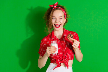 Poster - Photo portrait of lovely young lady wink milk glass cookie dressed stylish red retro garment isolated on green color background