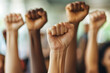 © Uwe - Close up of multiethnic people's hands raising fists in the air, with strong wrists showing the spirit of struggle and solidarity