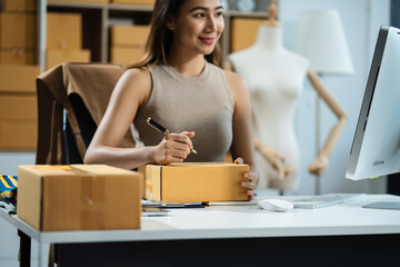 Wall Mural - woman start up small business owner writing address on cardboard box at workplace.small business entrepreneur SME or freelance America woman working with box at home.