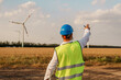© glebzter - Maintenance engineer checking wind turbine farm on a field. Portrait of skilled professional. European green deal