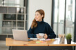 © Thitisak - ฺAsia Businesswoman sitting and working using laptop to chat with customers online in office