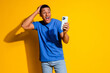 © deagreez - Photo portrait of attractive young man hold device excited dressed stylish blue clothes isolated on yellow color background