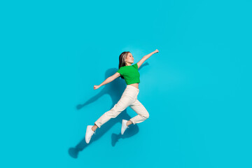 Full body portrait of pretty young girl jump empty space wear t-shirt isolated on turquoise color background