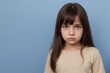 © PNG&Background Image - Young girl with angry or dissatisfied face standing against a blue background with copy space.