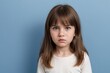 © PNG&Background Image - Young girl with angry or dissatisfied face standing against a blue background with copy space.