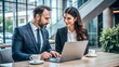 © N7 - A man and woman in formal attire discussing financial strategies, with a laptop open in front of them.