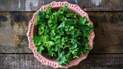 Wall Mural - Top view of a fresh salad with green kale in a decorative pink bowl, atop a natural wood surface