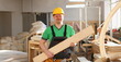 © H_Ko - Portrait of a smiling carpenter holding wood planks in a construction site