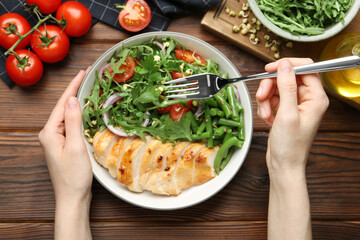 Healthy meal. Woman with bowl of tasty products at wooden table, top view