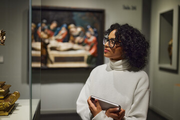 Woman visitor in the historical museum looking at art object.