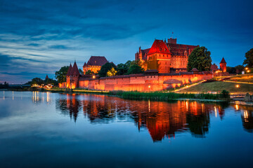 Wall Mural - Castle of theTeutonic Order in Malbork by the Nogat river at night with full moon.