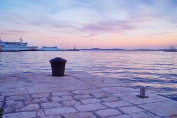 Wall Mural - Metall mooring bollard pole on sea pier in old croatia town on sunset