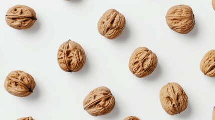 Pattern of whole walnuts on a white background, showcasing their textured shell in a minimalist, high-resolution photo.