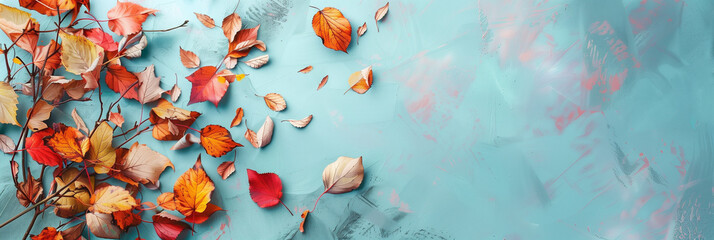 Colorful autumn foliage on blue background, fall season, orange, yellow and red colored leaves, copy space for text