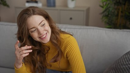 Canvas Print - A beautiful young blonde woman wearing a yellow sweater sits in her living room, smiling and relaxed at home.