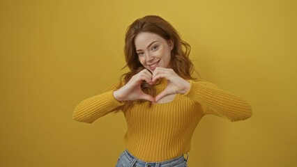 Poster - Young caucasian woman wearing sweater standing smiling in love showing heart symbol and shape with hands. romantic concept. over isolated yellow background