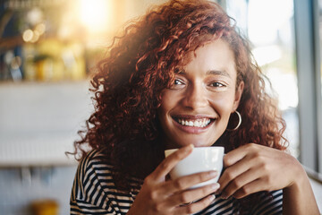 Wall Mural - African girl, portrait and coffee cup in cafe, restaurant and bistro to enjoy hot beverage with smile. Happy woman, espresso and cappuccino for drinking, caffeine and customer service in morning