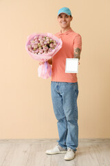 Canvas Print - Male courier with bouquet of roses and tablet computer near beige wall