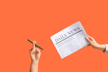 Poster - Female hands with newspaper and cigar on orange background