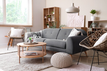 Sticker - Stylish interior of living room with black sofa, armchair, coffee table and shelving unit