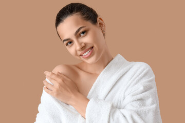 Sticker - Beautiful young happy woman in bathrobe on beige background