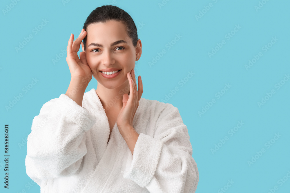 Beautiful young happy woman in bathrobe on blue background