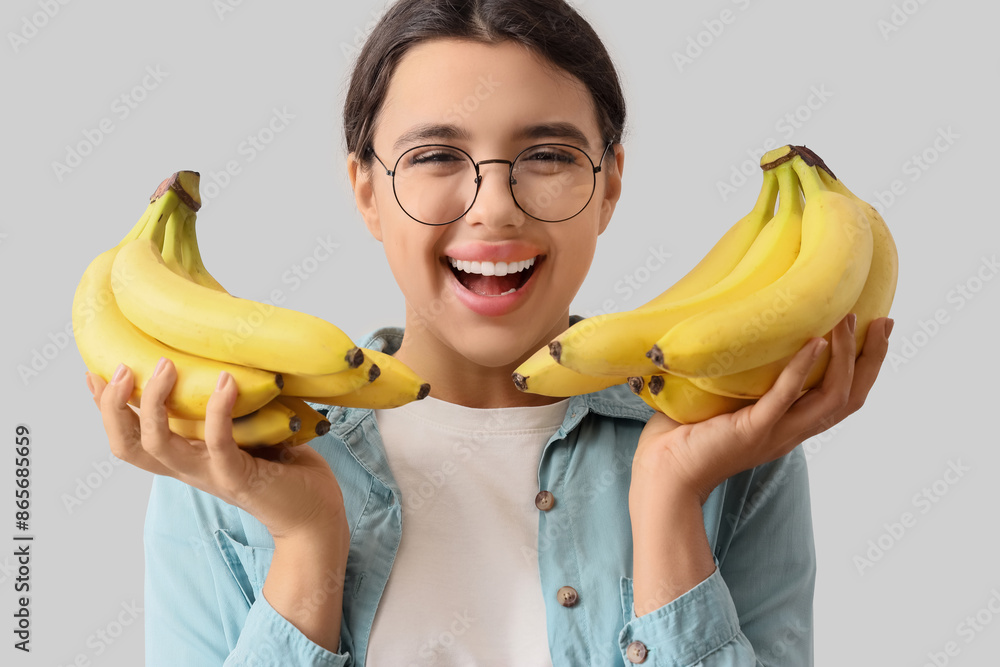 Happy young woman with bananas on light background, closeup