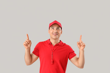 Wall Mural - Happy male lifeguard pointing at something on grey background