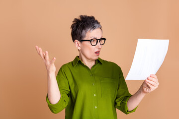 Wall Mural - Photo portrait of lovely pensioner lady read papers shocked dressed stylish green garment isolated on beige color background