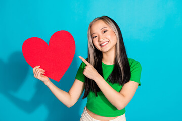 Wall Mural - Photo of nice young girl point finger empty space heart wear green t-shirt isolated on teal color background