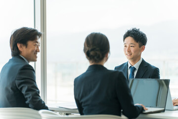 Poster - 企業のオフィスで笑顔で会議・ミーティング・商談をするアジア人ビジネスマンとビジネスウーマン
