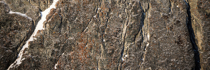Wall Mural - Rock texture. Snow and cracks on the surface of the cliff. Natural stone background.