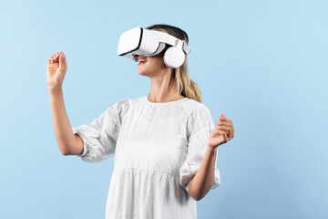 Wall Mural - Girl smells flower while wearing VR glasses at blue background. Happy woman with VR goggle enjoy looking nature hologram while connection with visual reality world. Technology innovation. Contraption.