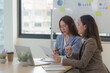 © Korakot - Two businesswomen discussing documents in an office, concept of teamwork and collaboration
