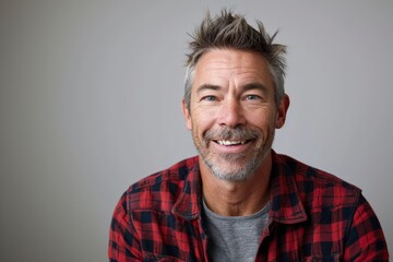 Portrait of a happy senior man smiling at the camera against a grey background