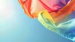 © penpirab - A rainbow flag waving gracefully in the wind with a clear blue sky background, leaving space on the right side for text