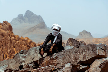 Guy from the desert sitting on the top of a mountain 