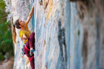 Wall Mural - Climber overcomes challenging climbing route. A girl climbs a rock. Woman engaged in extreme sport. .