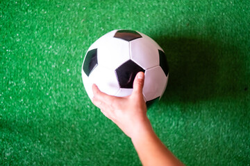 Hand Grips Soccer Ball on Grass Field