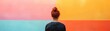© KanitChurem - Person with red hair in a bun, back view, standing against a vibrant, colorful wall divided into pink, orange, and teal sections.